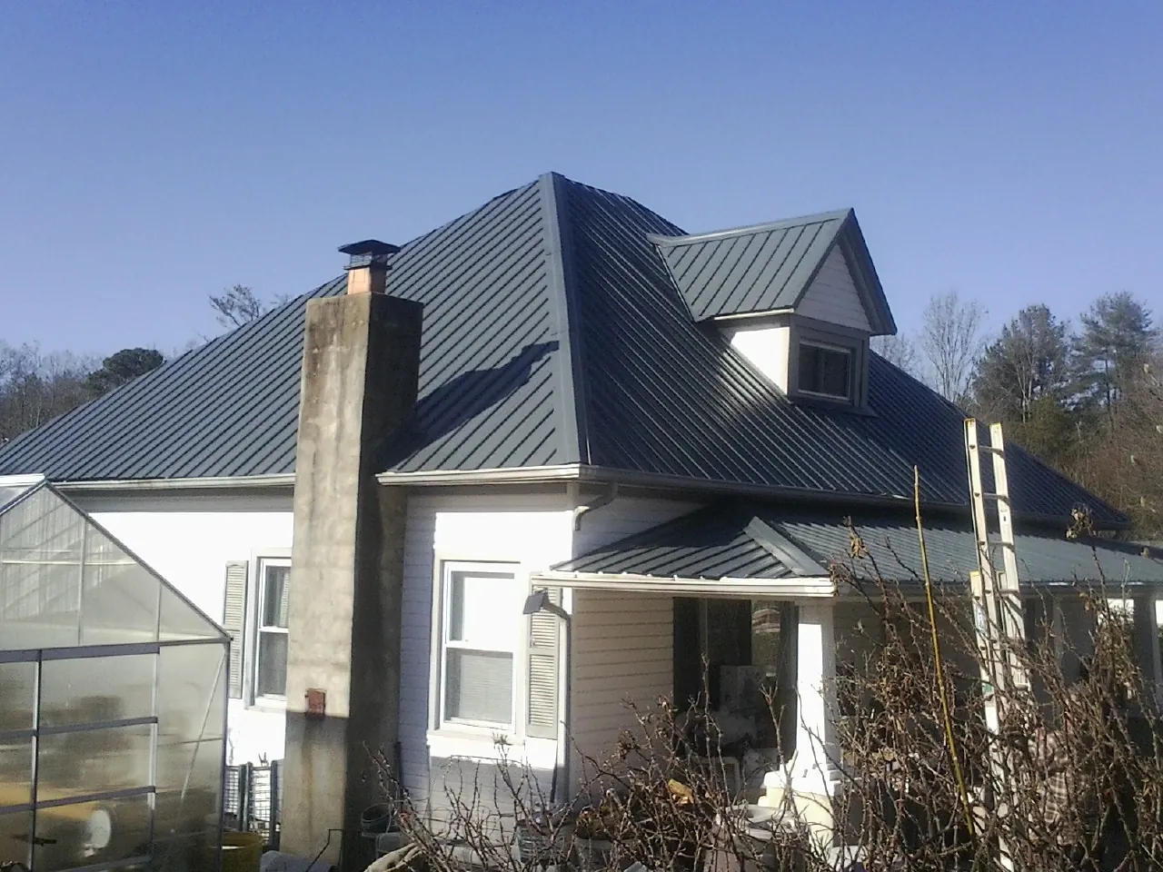 Dark blue standing seam metal roof on a white farmhouse with dormer — Slate & Tile Roof Repair by Roofing Brothers in Dracut