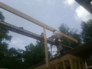 Carpenter setting a ridge beam over a new addition frame — Ice Dam Removal by Roofing Brothers in Dracut