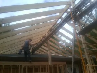 Rafters going up over a new addition with a worker on the wall in Dracut