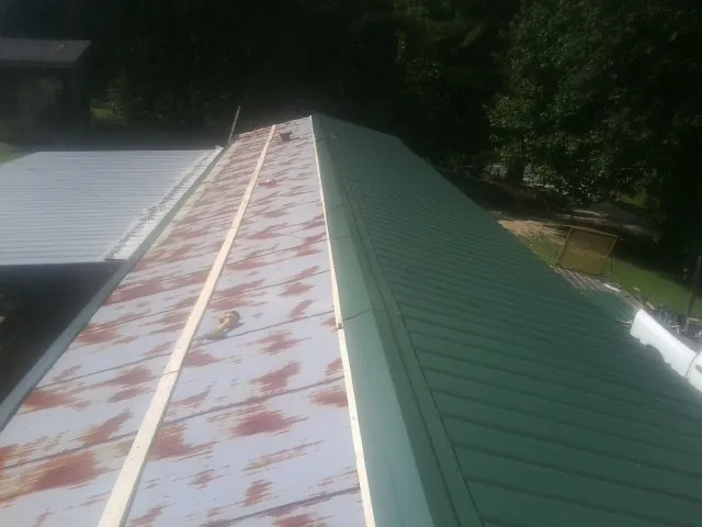Old rusted panels beside newly installed green metal roofing — Wind Damage Roof Repair by Roofing Brothers in Dracut