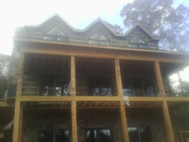 Dormers and porch framing on a large log home under construction — Roof Coating work by our crew in Dracut