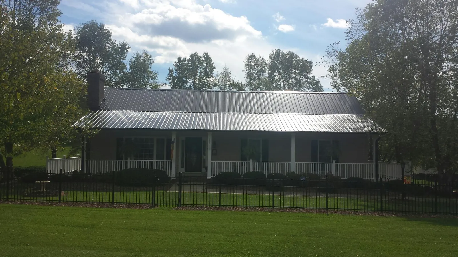 Gray metal roof on a brick ranch with a full width front porch — Gutter Guard Installation work by our crew in Dracut