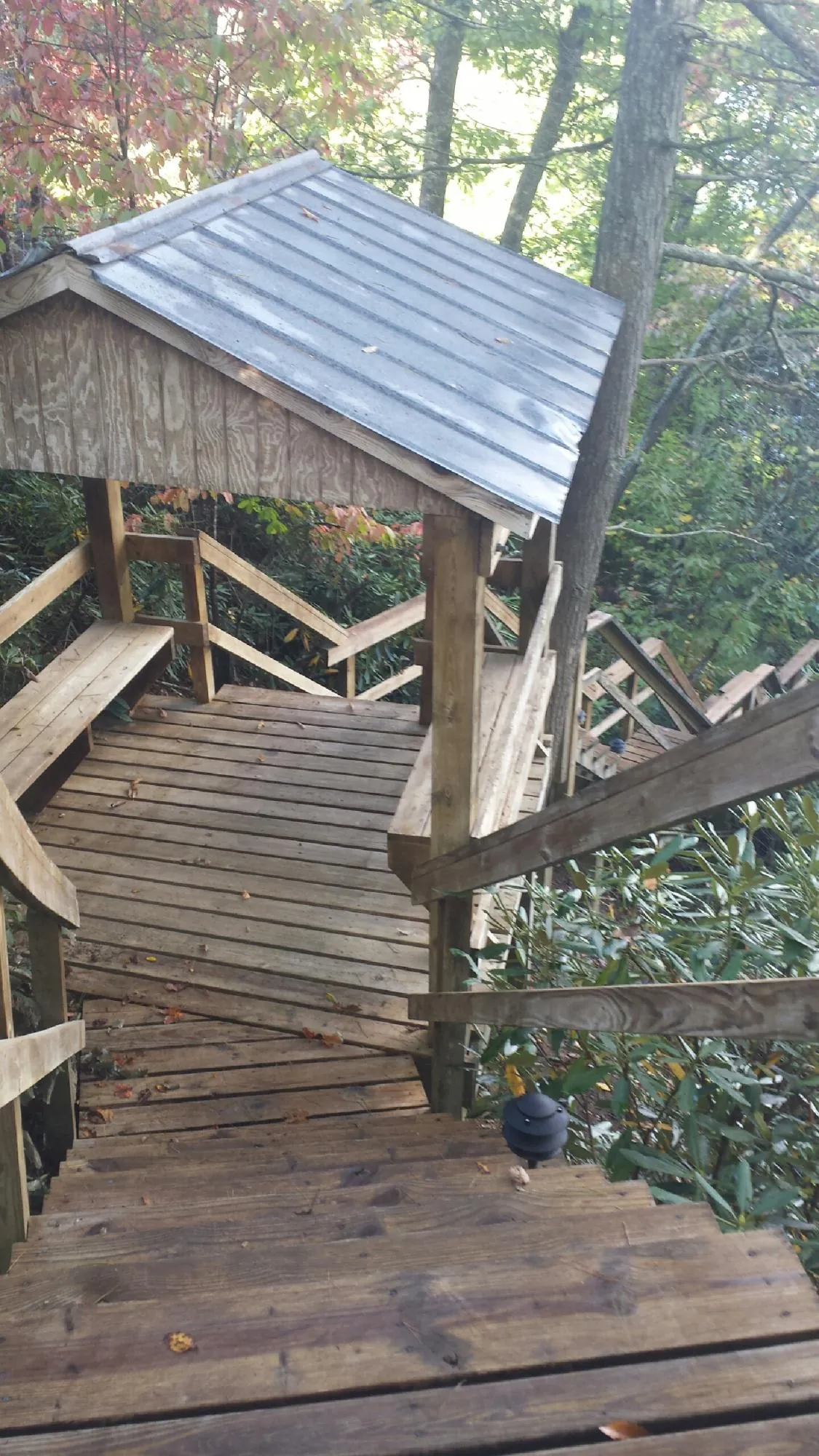 Metal roofed shelter over wooden steps on a wooded walkway — Skylight Repair & Installation work by our crew in Dracut