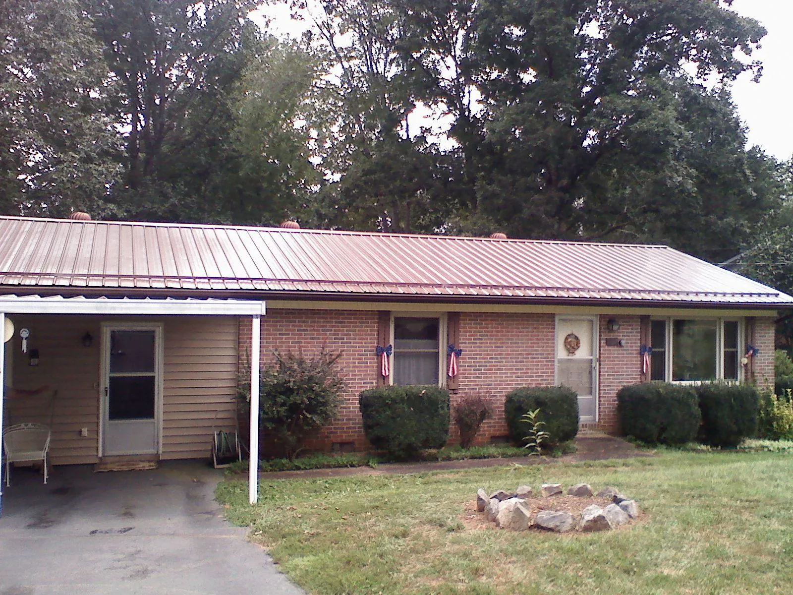 Bronze metal roof and carport on a brick ranch home — Roof Repair work by our crew in Dracut